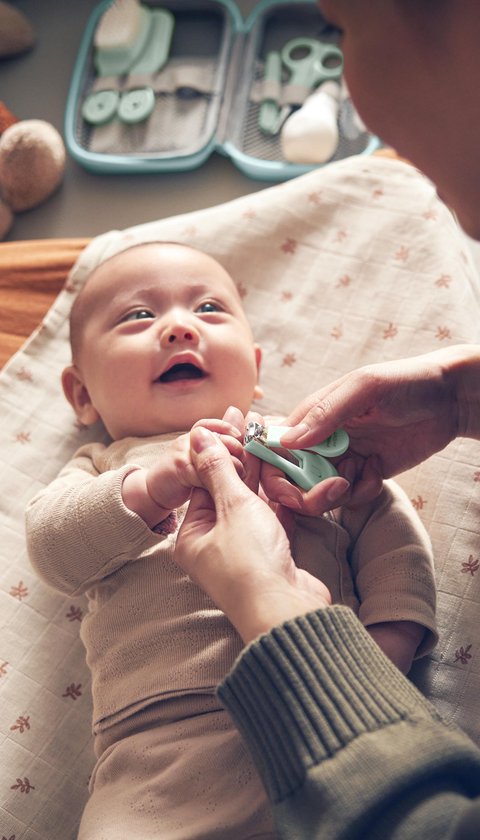 Baby wordt verzorgd door ouder met een mintgroene nagelknipper uit de babyverzorgingsset.
