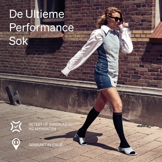 Vrouw in zwart-wit kleding met zwarte kniekousen met "STO" logo, zonnebril, wandelt buiten.