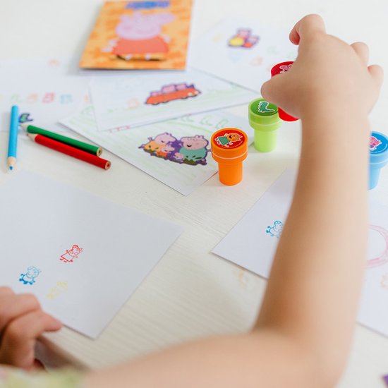 Kind stempelt Peppa Pig figuren op papier met rode, groene en blauwe stempels.