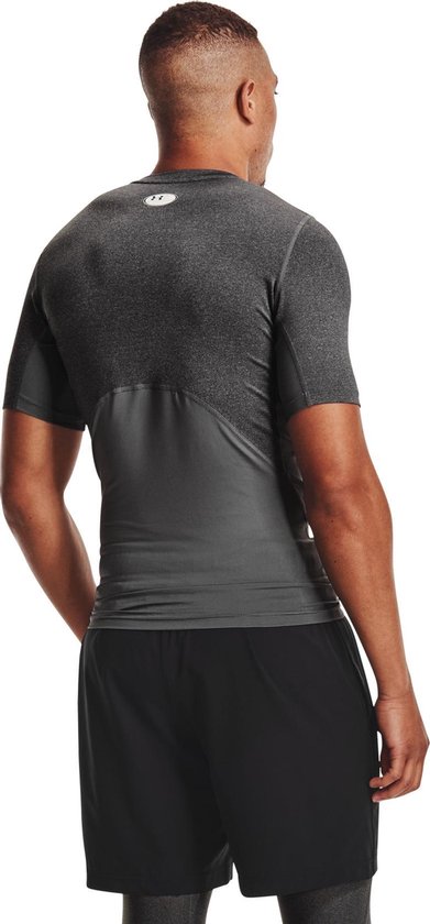 Man met donkergrijs, kort sportshirt met grijze panelen op de romp en rug.