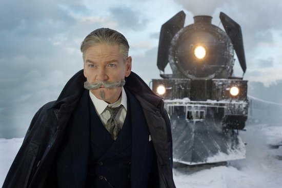 Een man met een snor en een donkere jas staat voor een stoomtrein.