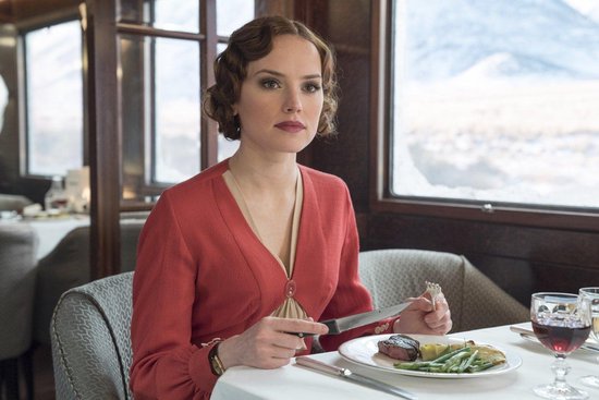 Een vrouw in een rode jurk zit aan tafel met een bord eten.