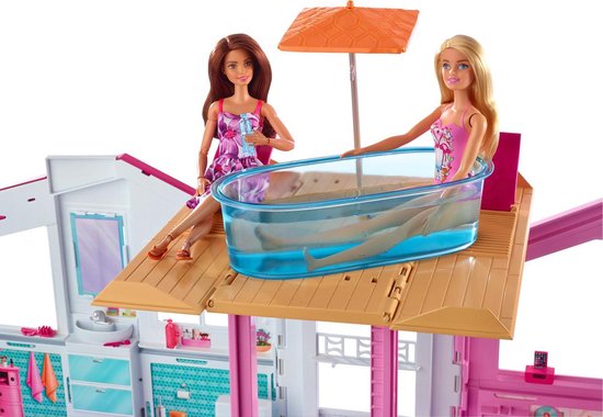 Twee Barbie poppen op een terras, één in een ligbad, bij een Barbie Malibu huis.