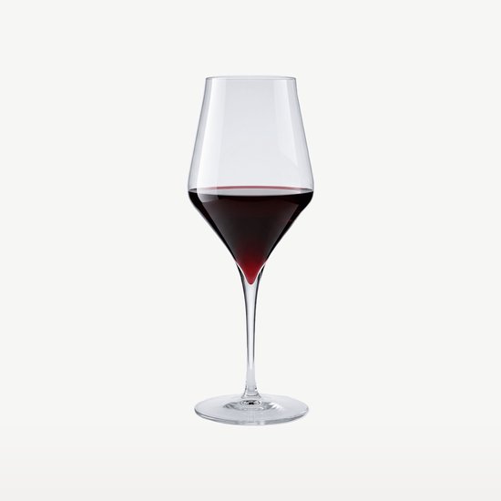Un seul verre à vin rempli de vin rouge, avec une subtile teinte rouge dans la tige.