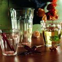 Trois verres Duralex Picardie transparents avec cannelures verticales, deux remplis de liquide jaune et de piments séchés, un vide.