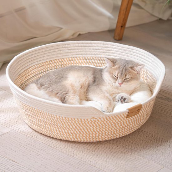 Un chat gris et blanc dort paisiblement dans un panier douillet tressé.