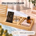 Houten badplank met telefoon, glas, kleine handdoek en flesje.