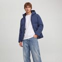 Model draagt een donkerblauwe pufferjack met capuchon en witte T-shirt.