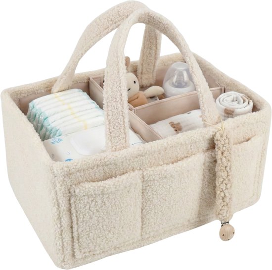 Sac à langer en teddy crème avec quatre compartiments, rempli de couches, un cordon pour tétine et une peluche.