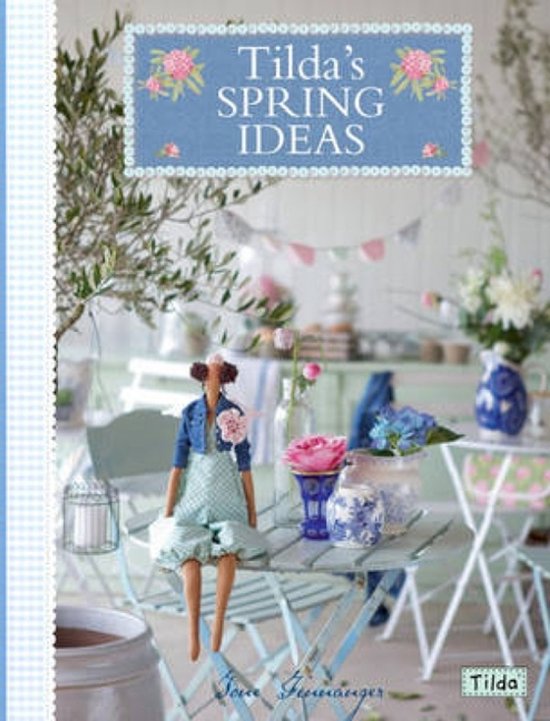Boekomslag 'Tilda's Spring Ideas' met een handgemaakte stoffen pop zittend aan een tafel in een lichte, bloemrijke tuin.