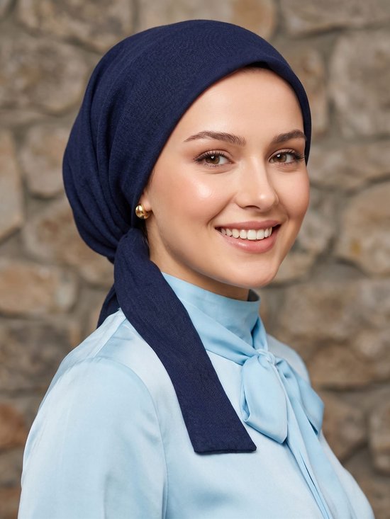Model draagt een donker marineblauwe katoenen hijab-bonnet met strikbanden, gecombineerd met een lichtblauwe blouse.