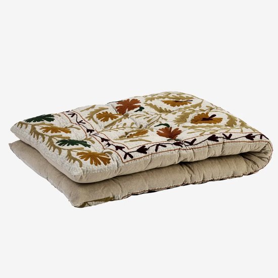 Opgevouwen geborduurd katoenen matras met florale patronen in oker, groen en oranje, zijkant in effen beige.