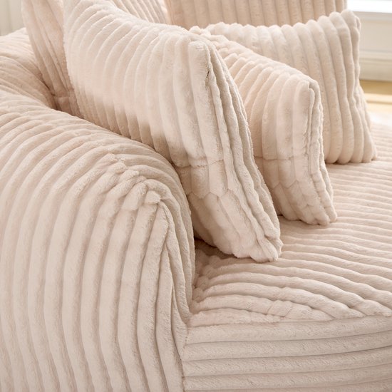 Close-up van de beige fluwelen stof met ribbelstructuur van de loungestoel en kussens.