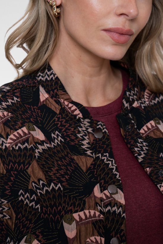 Close-up van een bomberjack met zwart, bruin en roze vogelpatroon.