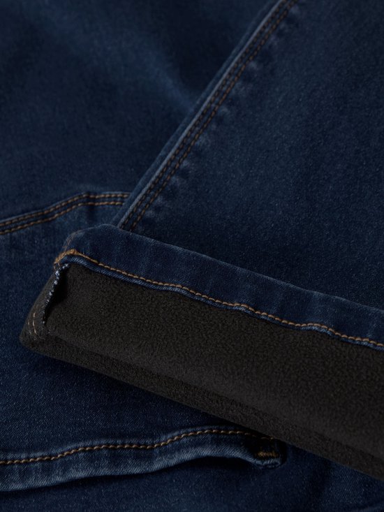 Detail van de omgeslagen broekspijp van donkerblauwe jeans met een zachte, zwarte fleecevoering.