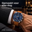 TYME Florence horloge met diepblauwe wijzerplaat en cognacbruine band, gedragen om een pols in een colbert.