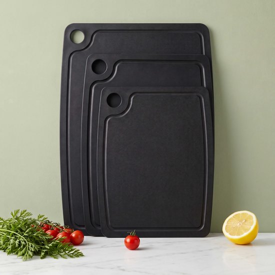 Drie zwarte snijplanken van verschillende groottes met fruit en groenten.