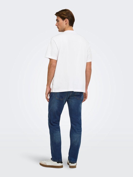 Achterzijde van een model met een wit T-shirt en blauwe jeans, gecombineerd met beige en witte sneakers.