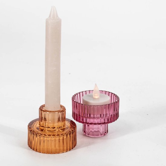 Amberkleurige en roze geribbelde glazen kandelaars, de een met een lange witte kaars, de ander met een led-waxinelichtje.