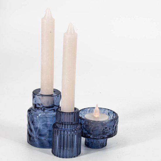Twee blauwe glazen kandelaars met beige kaarsen en een bijpassende theelichthouder met ledlichtje.