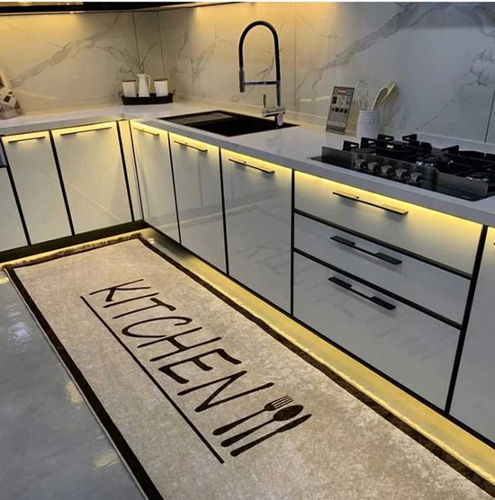 Crèmekleurige keukenloper met zwarte rand, de tekst 'KITCHEN' en een bestekicoon op een moderne keuken tegelvloer.