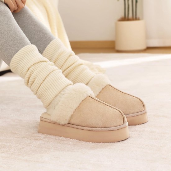 Zijaanzicht van model in grijze legging met crèmekleurige sokken en beige suède platformpantoffels.