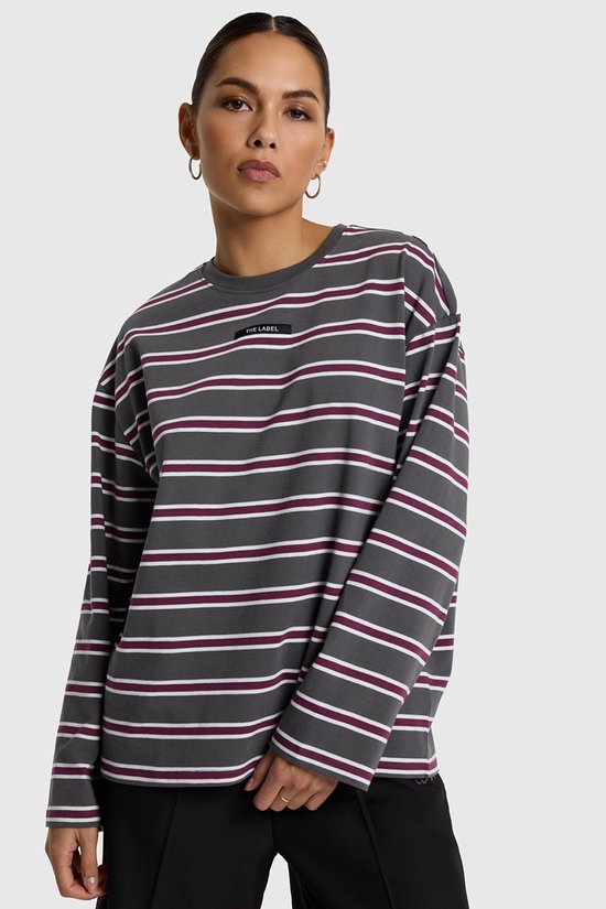 Model draagt een donkergrijs longsleeve T-shirt met horizontale strepen in wit en bordeaux, en een "THE LABEL" borstlogo.