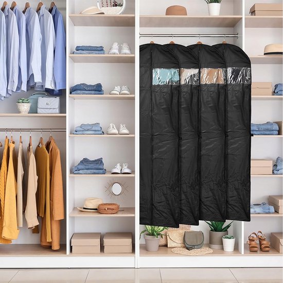 Vier zwarte kledinghoezen hangend in een kledingkast tussen kleding en schoenen.