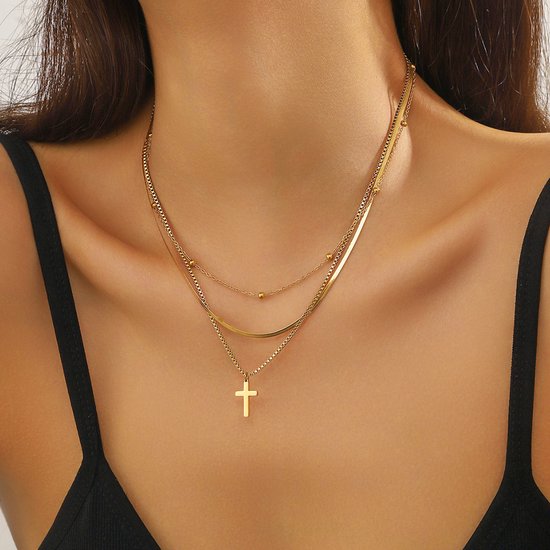 Gouden multistraks ketting met kruishanger gedragen door een vrouw.