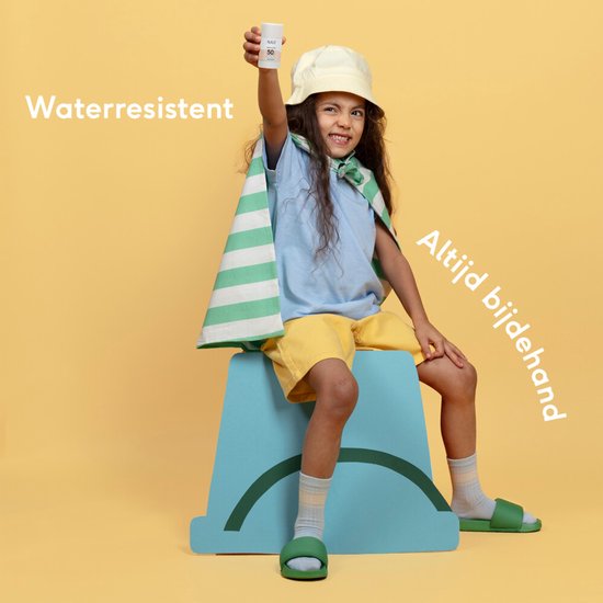 Meisje met zonnebrand stick 50, zonnehoed en cape om haar schouders