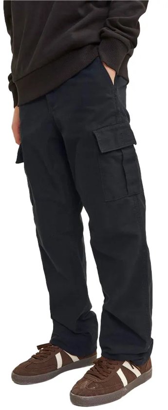 Jongensmodel in zwarte cargo broek met cargo zakken op de zijkant, bruine sneakers met strepen.