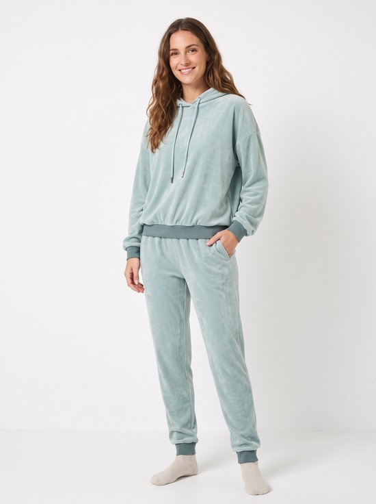 Model draagt een lichtblauw fleece huispak met capuchon, trekkoord en boorden bij de polsen en enkels.