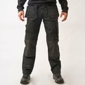 Model in zwarte werkbroek met versterkte kniestukken en meerdere zakken, staand op een witte achtergrond.