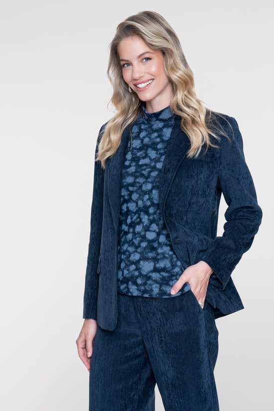 Model draagt een blauwe top met dierenprint en glitterdetails, gecombineerd met een bijpassende blazer en broek.