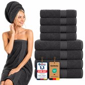 Model met een donkergrijze handdoek om haar hoofd en een om haar lichaam. Naast haar een stapel donkergrijze handdoeken met "SEHR GUT" en "OEKO TEX" labels.