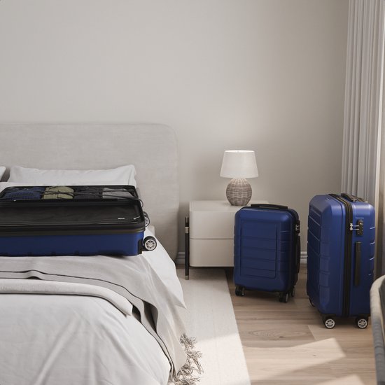 Een geopende donkerblauwe koffer en twee gesloten koffers naast een bed.