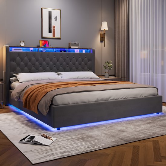 Donkergrijs gestoffeerd bed met capitonnering in het hoofdbord, houten legplanken en LED-verlichting. De onderrand van het bed heeft ook LED-verlichting.