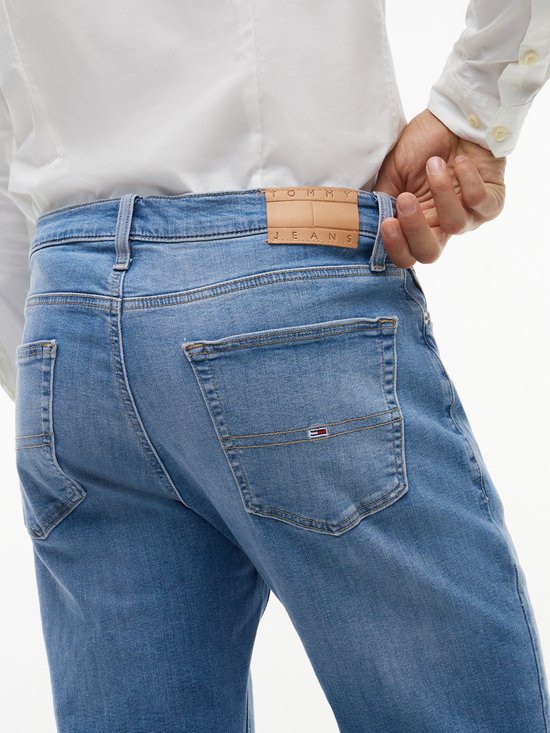 Detail van de achterkant van een lichte spijkerbroek met Tommy Jeans logo.