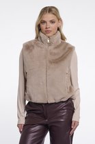 Model draagt een korte, bruine teddy bodywarmer met rits en hoge kraag, over een beige top en donkerbruine leren broek.