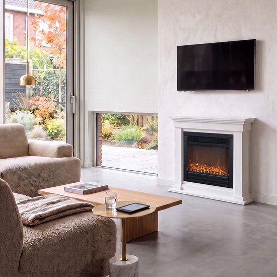 Moderne witte schouw met een brandend elektrisch vuur, een Samsung tv erboven, en een beige fauteuil ernaast.