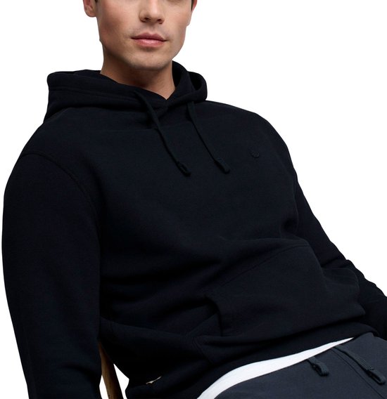 Man zit en draagt een donkerblauwe Superdry hoodie met capuchon en kangoeroezak.