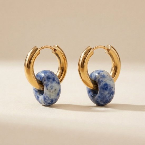 Paar gouden oorringen met een blauw-witte natuursteen hanger, geïsoleerd op een lichte achtergrond.