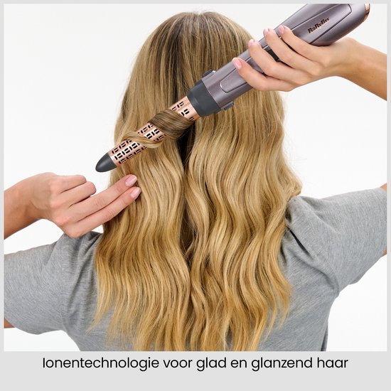 Achterkant van vrouw die haar haar in zachte golven stylet met de ionische föhnborstel.