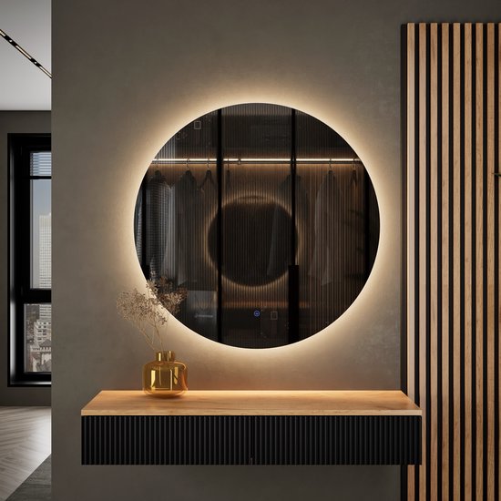 Ronde LED-spiegel gemonteerd boven een moderne zwarte console met houten accenten in een hal.