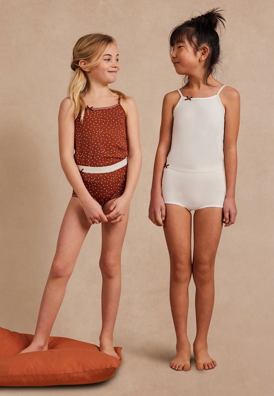 Twee meisjes dragen Ten Cate ondergoed: één in bruin met stippen, één in off-white, beiden met topjes.