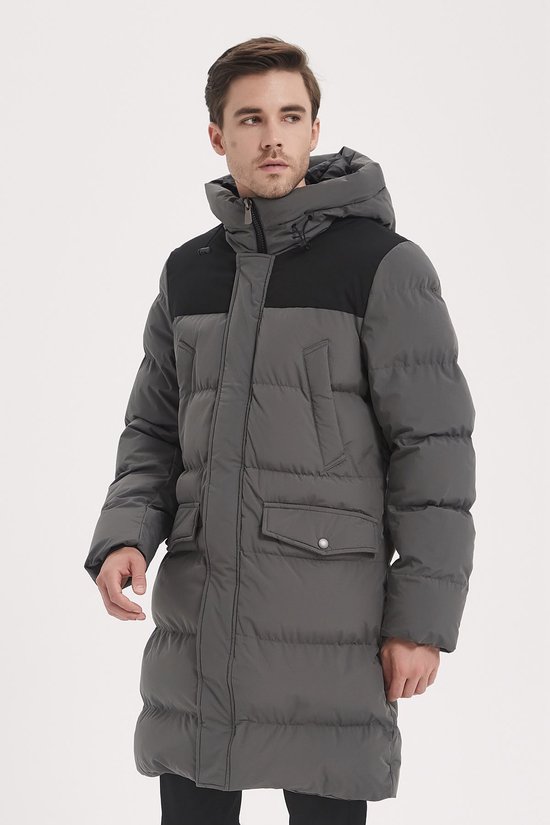 Model in profiel draagt een lange grijze gewatteerde parka met capuchon en zwarte schouderinzet.
