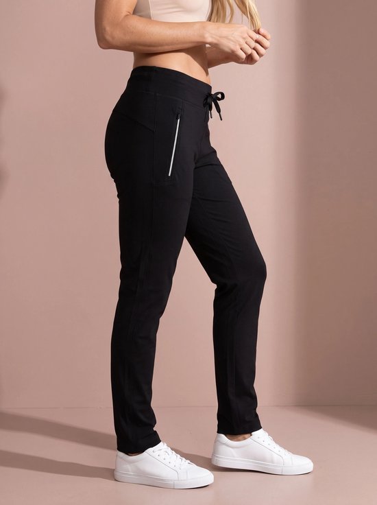 Zijaanzicht van een zwarte sportbroek met trekkoord in de taille, zak met witte rits en witte sneakers.