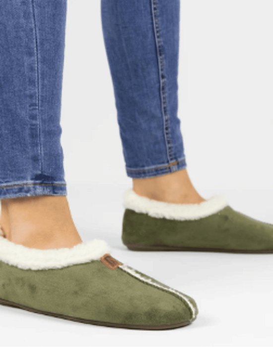 Model draagt olijfgroene pantoffels met witte imitatiebontrand onder een blauwe jeans.