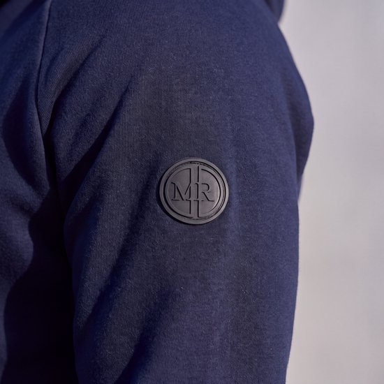 Detail van het ronde Mario Russo-embleem met MR-letters op de mouw van de hoodie.