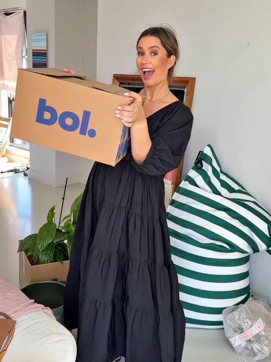Vrouw in een zwarte jurk houdt een kartonnen doos met het blauwe 'bol.' logo vast naast een groen-wit gestreepte zitzak.